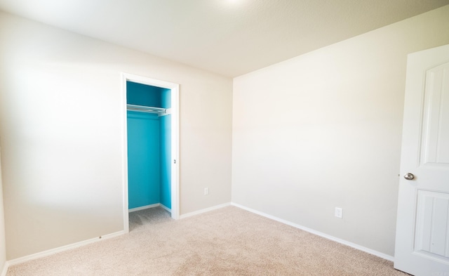 unfurnished bedroom featuring light carpet and a closet