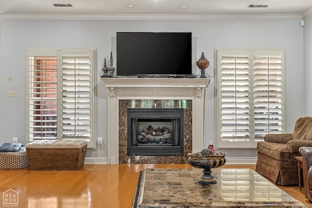 living room featuring a healthy amount of sunlight, crown molding, and a high end fireplace