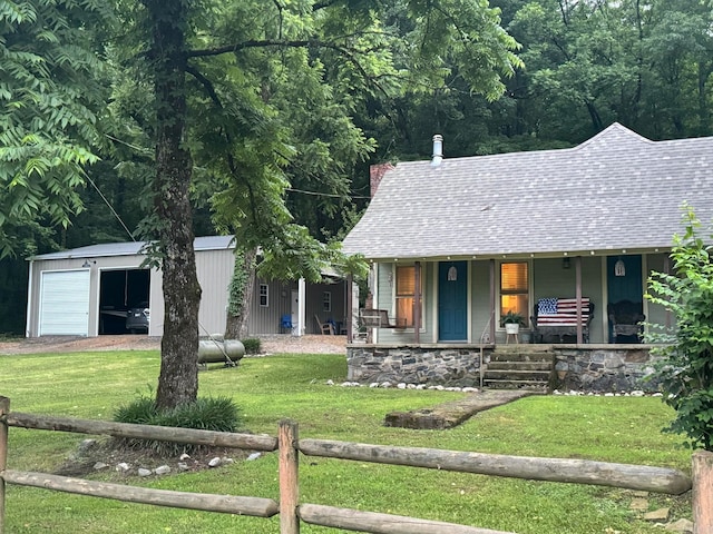 view of front of house featuring a garage, an outbuilding, a front yard, and covered porch