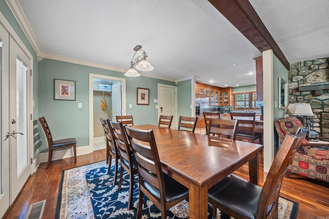 dining area featuring baseboards, visible vents, ornamental molding, dark wood-type flooring, and a textured ceiling