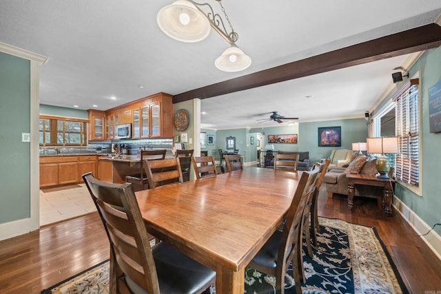 dining area with light wood finished floors, baseboards, a ceiling fan, and crown molding