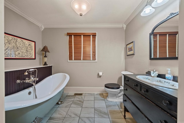 full bath with baseboards, toilet, vanity, crown molding, and a freestanding bath