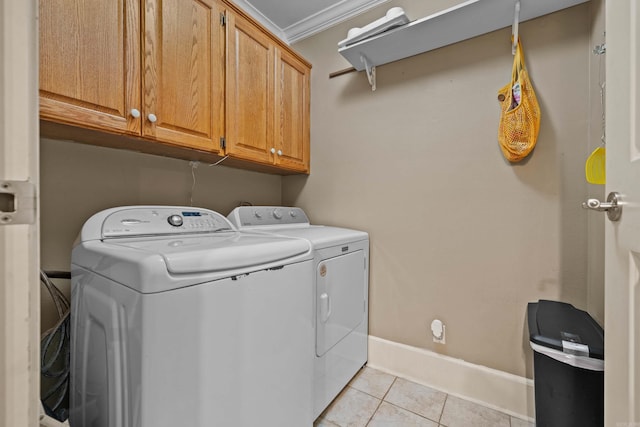 washroom with light tile patterned flooring, baseboards, washer and dryer, ornamental molding, and cabinet space