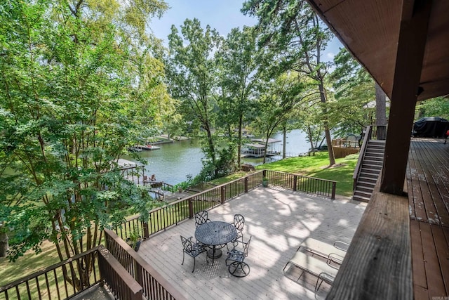 wooden deck featuring stairway, outdoor dining area, and a water view