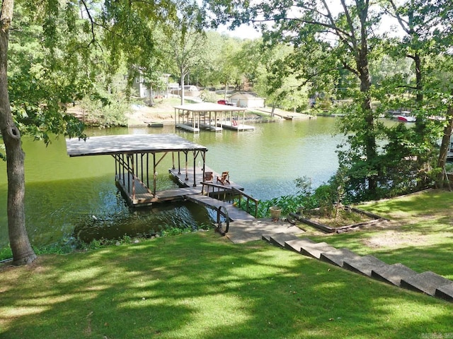 dock area featuring a water view, boat lift, and a yard