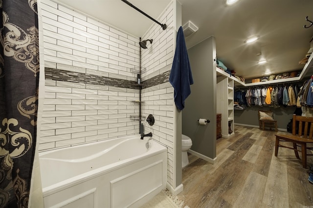 bathroom with tiled shower / bath combo, toilet, and wood-type flooring