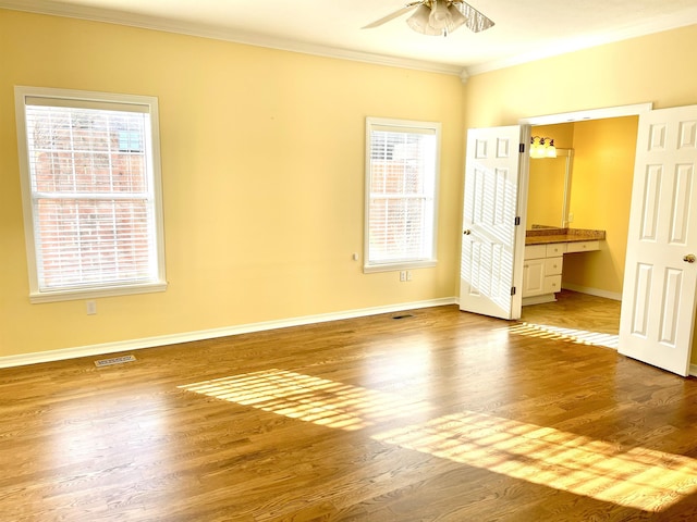 unfurnished bedroom featuring crown molding, connected bathroom, and hardwood / wood-style floors