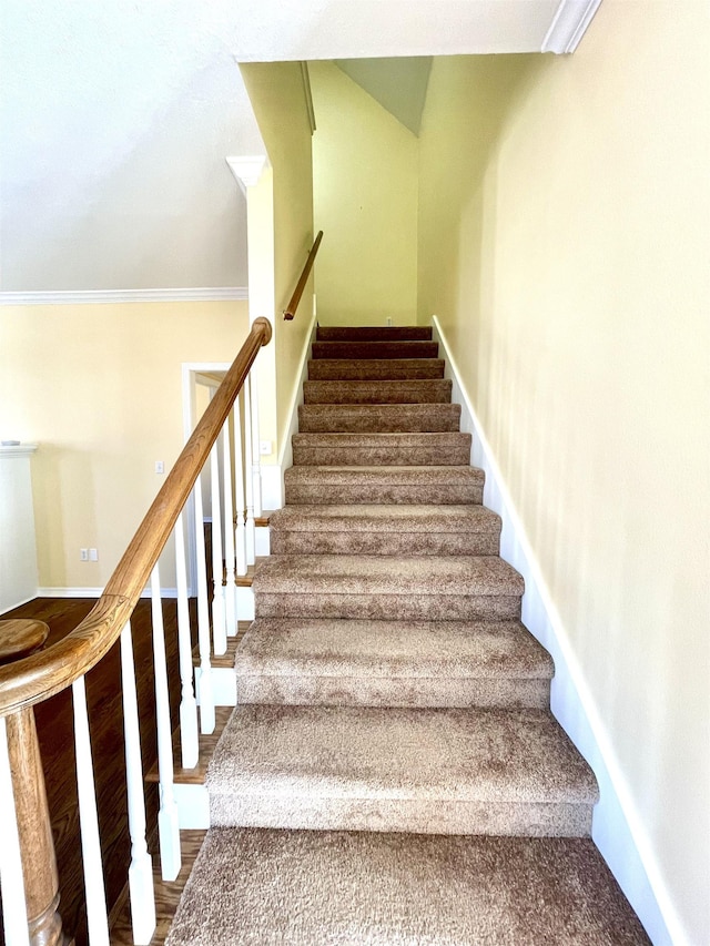 stairs with wood-type flooring and ornamental molding