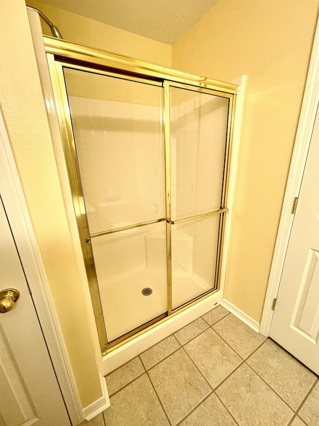 bathroom with a shower with shower door and tile patterned flooring