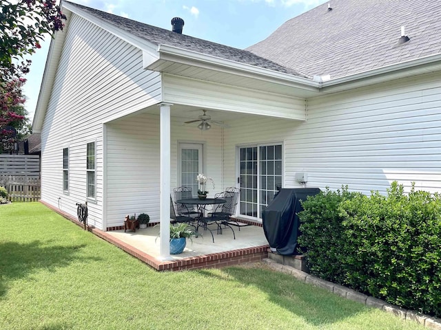 rear view of property featuring ceiling fan, a patio, and a lawn