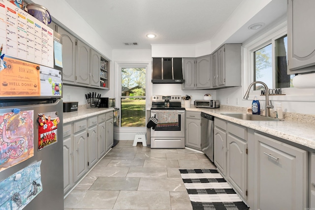 kitchen with light tile patterned floors, wall chimney range hood, stainless steel appliances, sink, and gray cabinetry