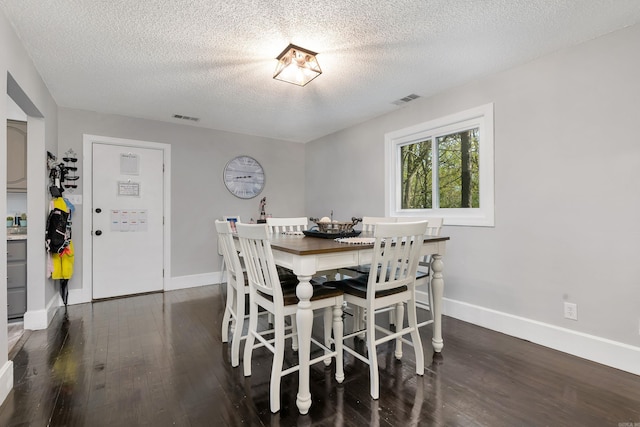 dining area with a textured ceiling and dark hardwood / wood-style floors