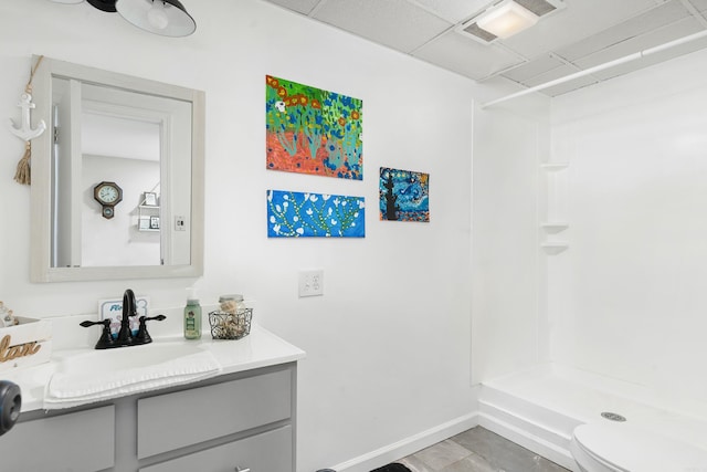 bathroom with a shower, toilet, vanity, and a paneled ceiling