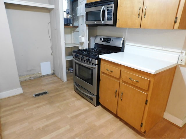 kitchen with appliances with stainless steel finishes and light hardwood / wood-style floors