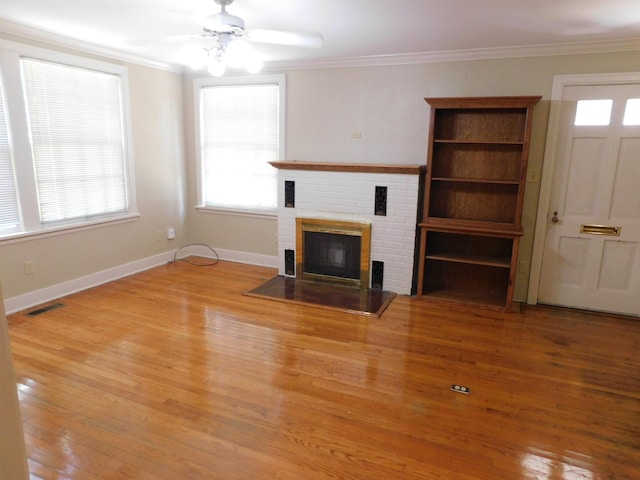 unfurnished living room with hardwood / wood-style floors, a fireplace, ornamental molding, and ceiling fan