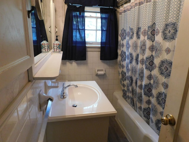 bathroom with tile walls, sink, and shower / bath combination with curtain