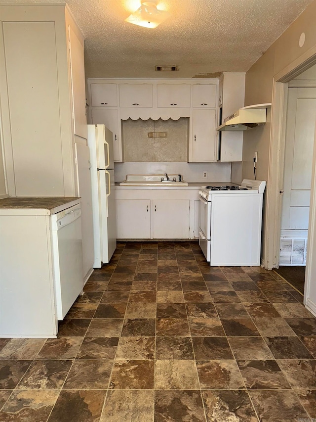 kitchen with white cabinetry, dark tile patterned floors, and white appliances