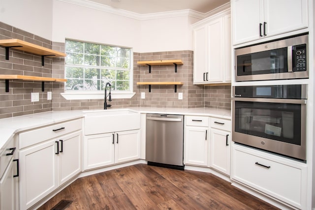 kitchen featuring appliances with stainless steel finishes, sink, decorative backsplash, crown molding, and dark wood-type flooring