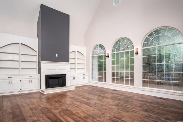 unfurnished living room featuring built in shelves, hardwood / wood-style flooring, and high vaulted ceiling