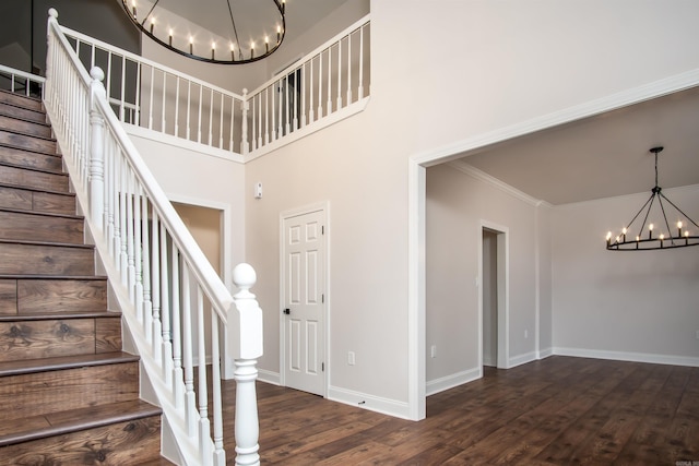 stairs featuring a towering ceiling, crown molding, dark hardwood / wood-style floors, and a chandelier