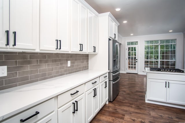 kitchen with appliances with stainless steel finishes, decorative backsplash, white cabinetry, dark wood-type flooring, and ornamental molding