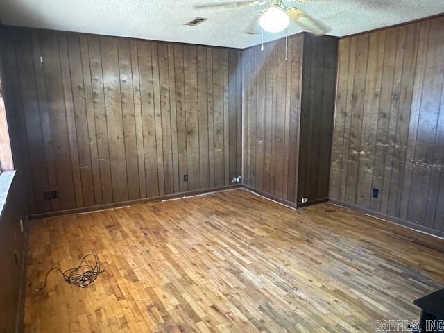 spare room with visible vents, ceiling fan, a textured ceiling, and wood finished floors