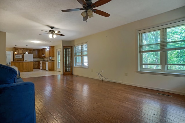 unfurnished living room featuring sink, light hardwood / wood-style flooring, and ceiling fan