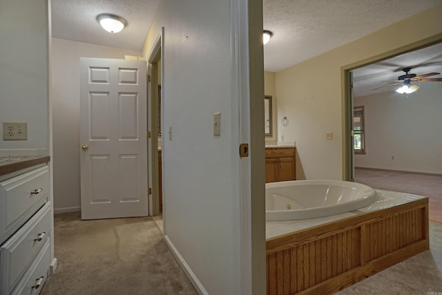 bathroom featuring vanity, a textured ceiling, ceiling fan, and a tub to relax in