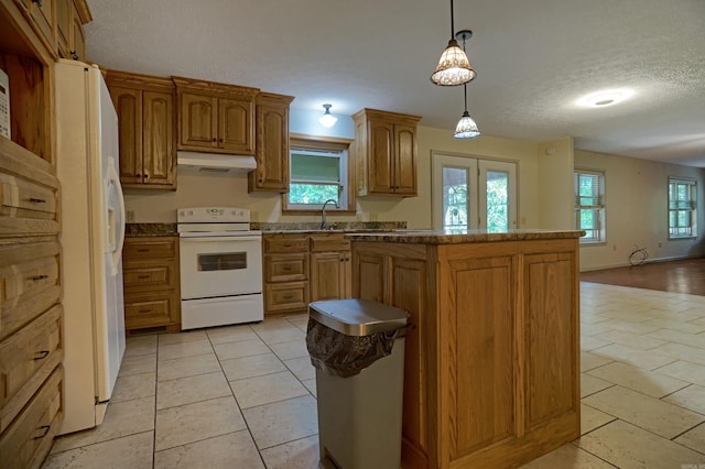 kitchen with decorative light fixtures, white appliances, a wealth of natural light, and light tile patterned floors