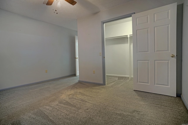 unfurnished bedroom featuring a closet, carpet floors, ceiling fan, and a spacious closet