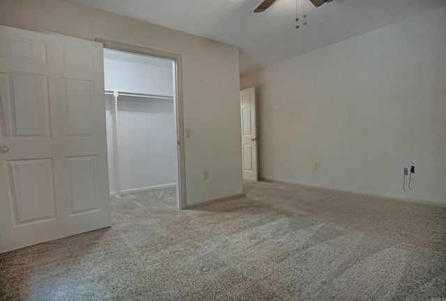 unfurnished bedroom featuring a spacious closet, light colored carpet, a closet, and ceiling fan