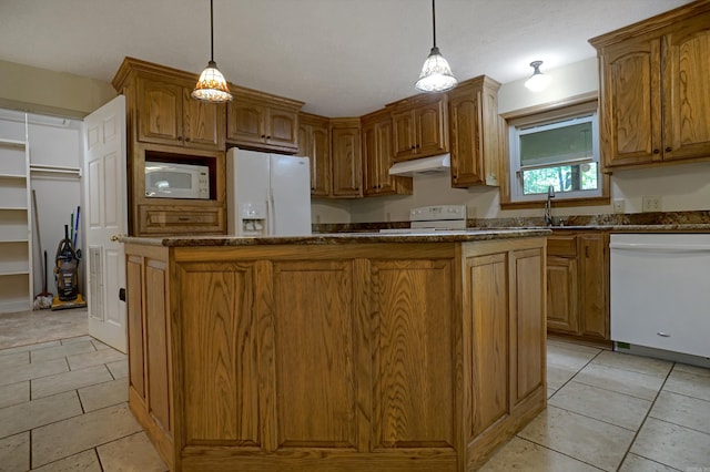 kitchen with a center island, pendant lighting, white appliances, and light tile patterned floors