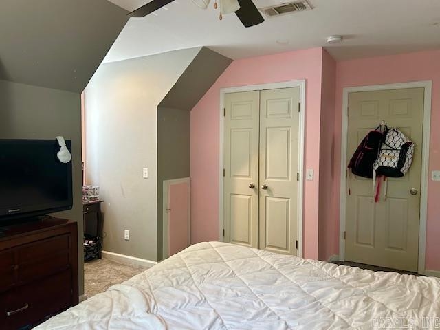 carpeted bedroom with ceiling fan, lofted ceiling, and a closet