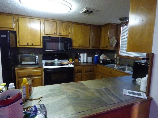 kitchen featuring sink, a textured ceiling, and black appliances