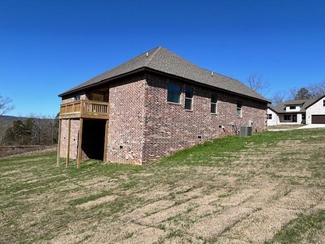 view of side of home featuring cooling unit and a lawn