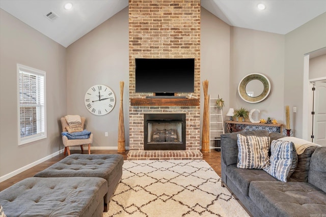 living room with a brick fireplace, hardwood / wood-style flooring, and high vaulted ceiling