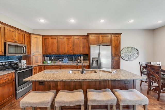 kitchen with stainless steel appliances, sink, and a center island with sink