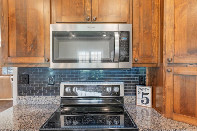 kitchen with stone counters, electric range, and backsplash