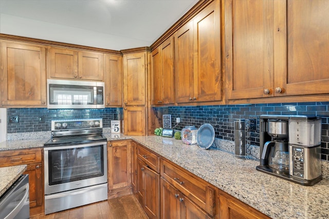 kitchen with decorative backsplash, dark wood-type flooring, light stone countertops, and appliances with stainless steel finishes