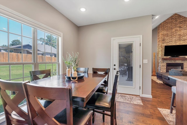 dining area featuring a brick fireplace and dark hardwood / wood-style floors