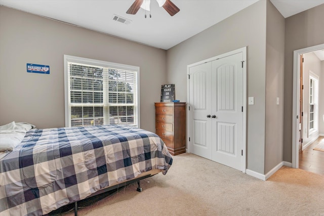 bedroom featuring light colored carpet, a closet, and ceiling fan