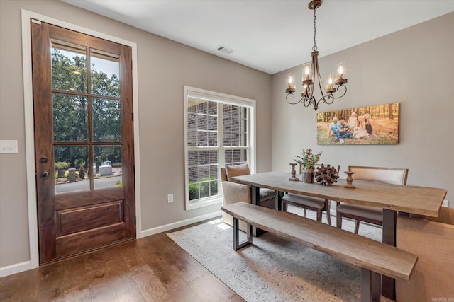 dining space with dark wood-type flooring and a chandelier