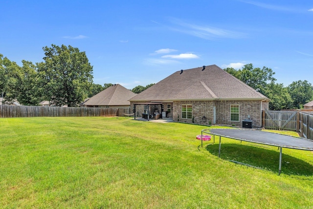 back of house featuring cooling unit, a yard, a patio area, and a trampoline