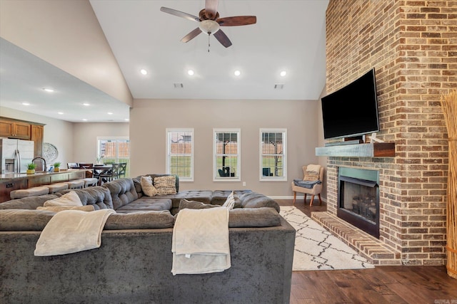 living room with ceiling fan, high vaulted ceiling, a fireplace, and dark hardwood / wood-style flooring