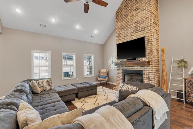 living room featuring dark wood-type flooring, ceiling fan, high vaulted ceiling, and a brick fireplace