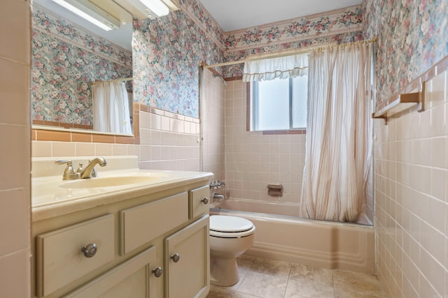 full bathroom with shower / tub combo with curtain, tile walls, tile patterned flooring, vanity, and toilet