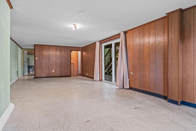 unfurnished living room with a textured ceiling and wood walls