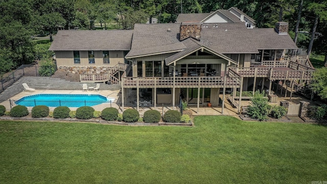 rear view of house with a swimming pool side deck and a lawn