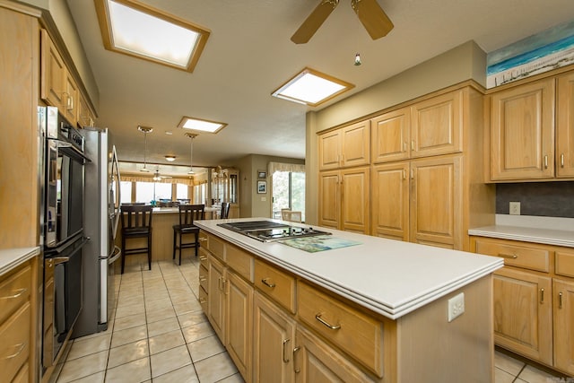 kitchen featuring light tile patterned floors, ceiling fan, stainless steel gas cooktop, a kitchen island, and decorative light fixtures