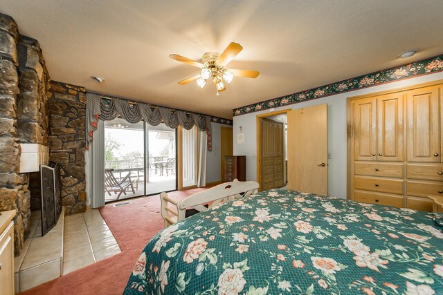 tiled bedroom featuring ceiling fan, a stone fireplace, and access to outside